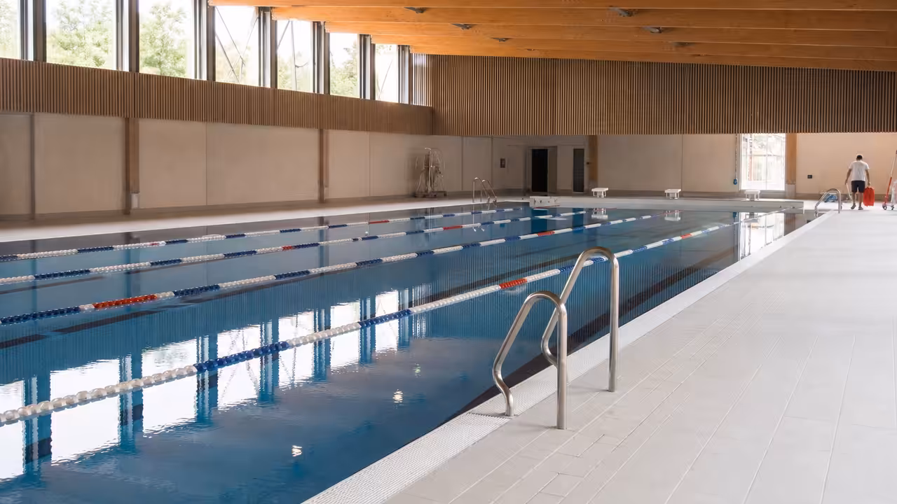 Bassin municipal rénové et lumineux, avec lignes d’eau, vestiaires vitrés et personnel en préparation