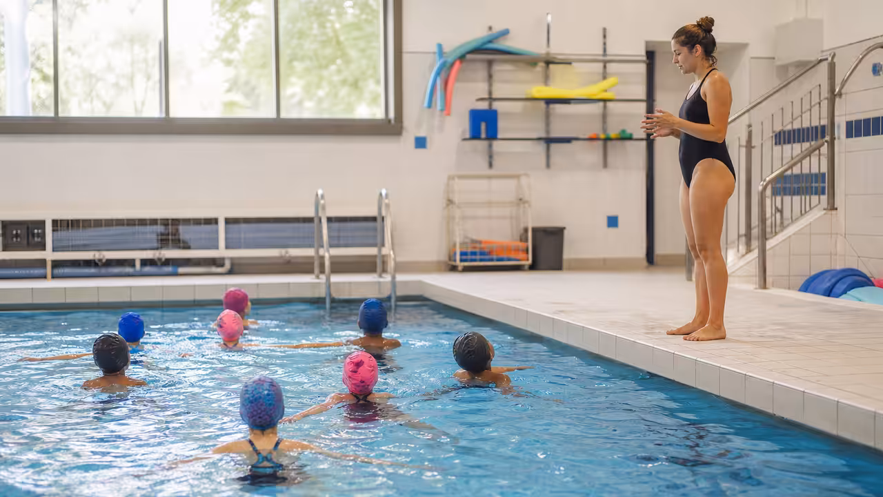Groupe d’écoliers de dos suivant une séance d’apprentissage de la natation dans un bassin couvert