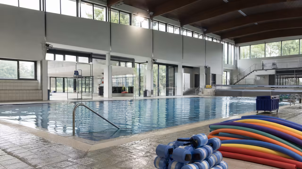 Maître-nageuse préparant du matériel d’aquagym au bord d’un bassin municipal vide avant un cours