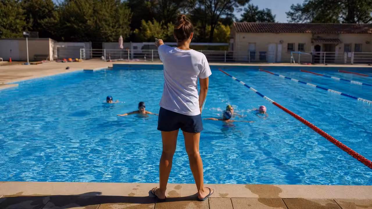 Enfants encadrés lors d’un cours de natation dans un bassin extérieur municipal en été