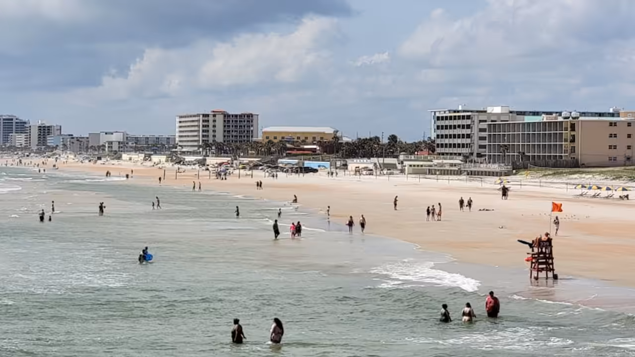 Bassin extérieur d’une piscine municipale avec lignes d’eau, plage minérale et baigneurs vus de loin