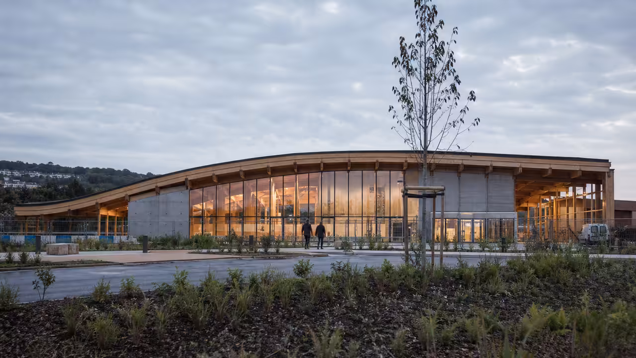 Vue extérieure d’un centre aquatique moderne avec bassin de nage et grandes façades vitrées au crépuscule