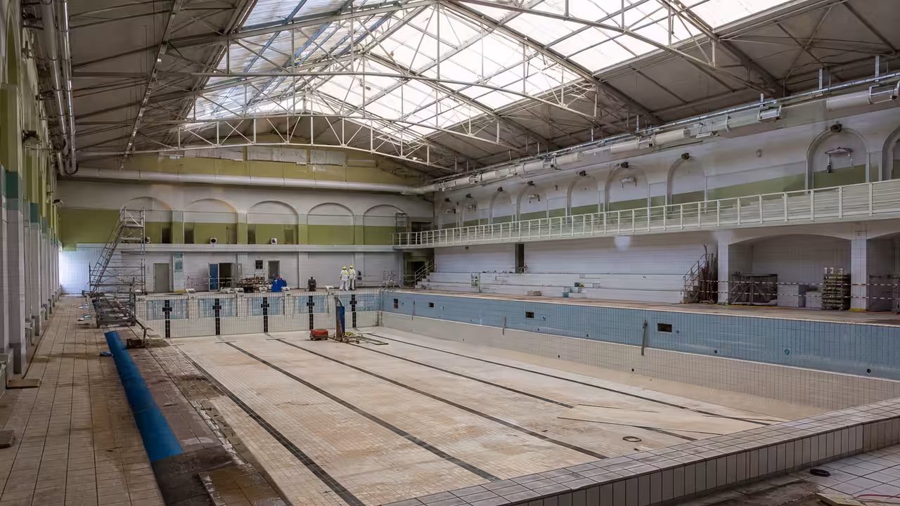 Bassin couvert vide sous une charpente ancienne, préparé pour une rénovation de toiture