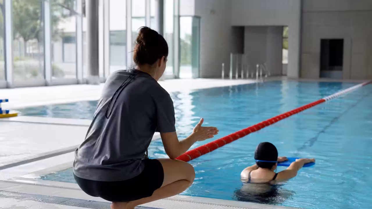 Maître-nageur encadrant une leçon individuelle de natation dans un bassin couvert lumineux