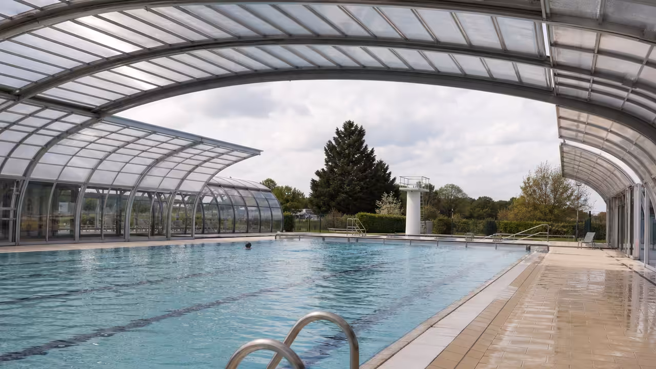 Toit rétractable partiellement ouvert au-dessus d’un bassin de piscine publique par temps lumineux