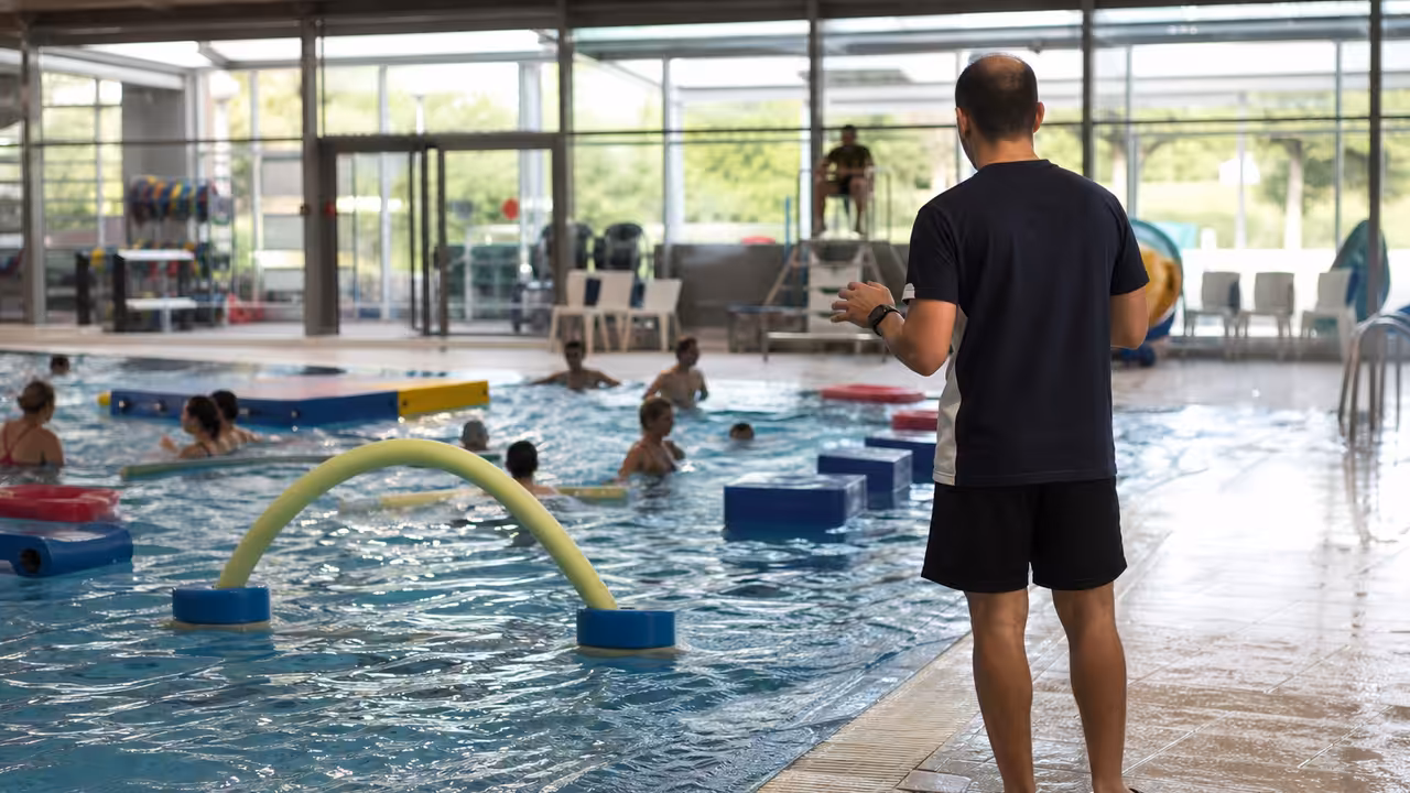 Animation aquatique encadrée dans un bassin public avec parcours flottant et nageurs adultes