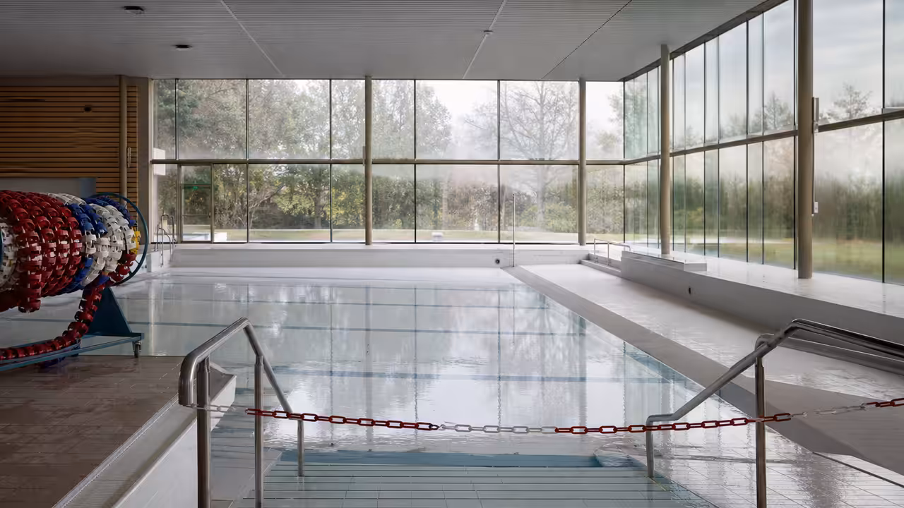 Agent de piscine inspectant une clôture près d’un bassin municipal après une intrusion animale