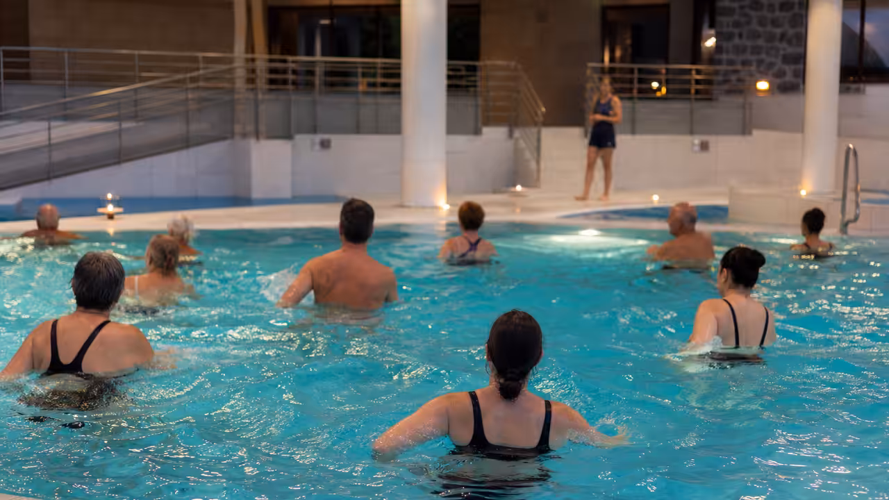 Participants adultes effectuant des exercices de nage et de renforcement dans un bassin couvert