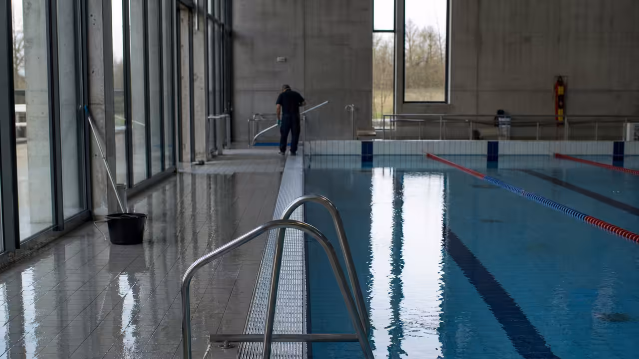 Bassin sportif intérieur d’une piscine publique avec lignes d’eau et gradins vides en arrière-plan