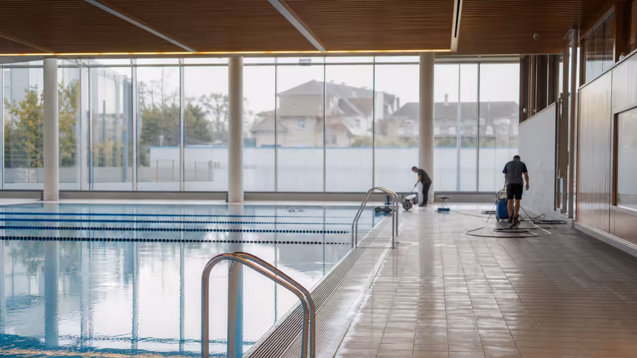 Bassin d’un centre aquatique municipal avec lignes d’eau et personnels préparant l’ouverture matinale