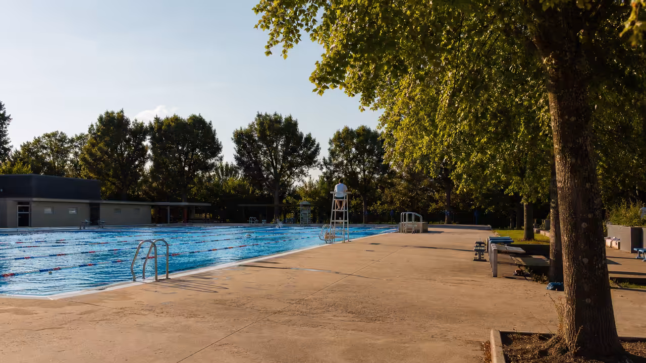 Bassin extérieur d’une piscine municipale avec lignes de nage, zones ombragées et surveillance estivale