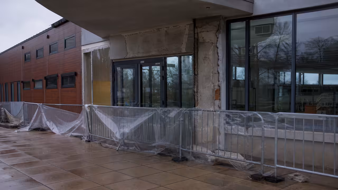 Entrée vitrée d’une piscine municipale temporairement sécurisée par des barrières après des dégâts matériels