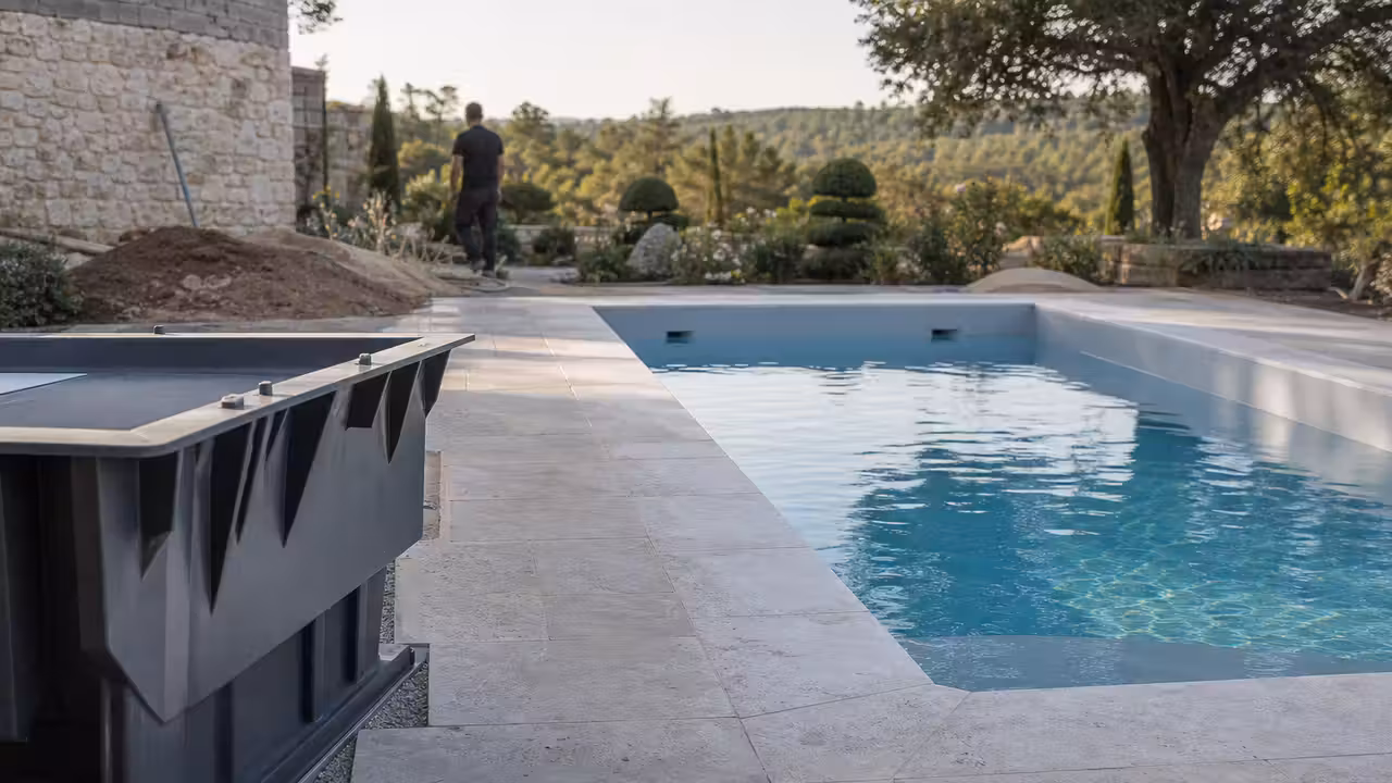 Piscine enterrée contemporaine aux lignes droites, terrasse minérale et jardin paysager en lumière naturelle