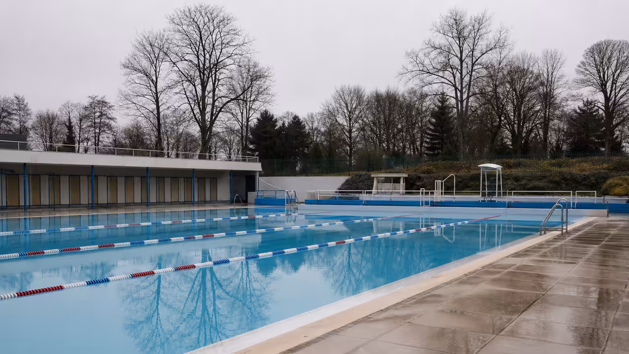 Bassin extérieur de piscine publique vide en hiver, avec lignes d’eau et plages humides sans baigneurs
