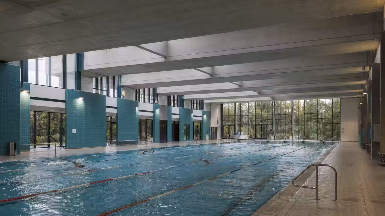 Hall lumineux d’une piscine municipale contemporaine avec bassin sportif à couloirs et structure en béton