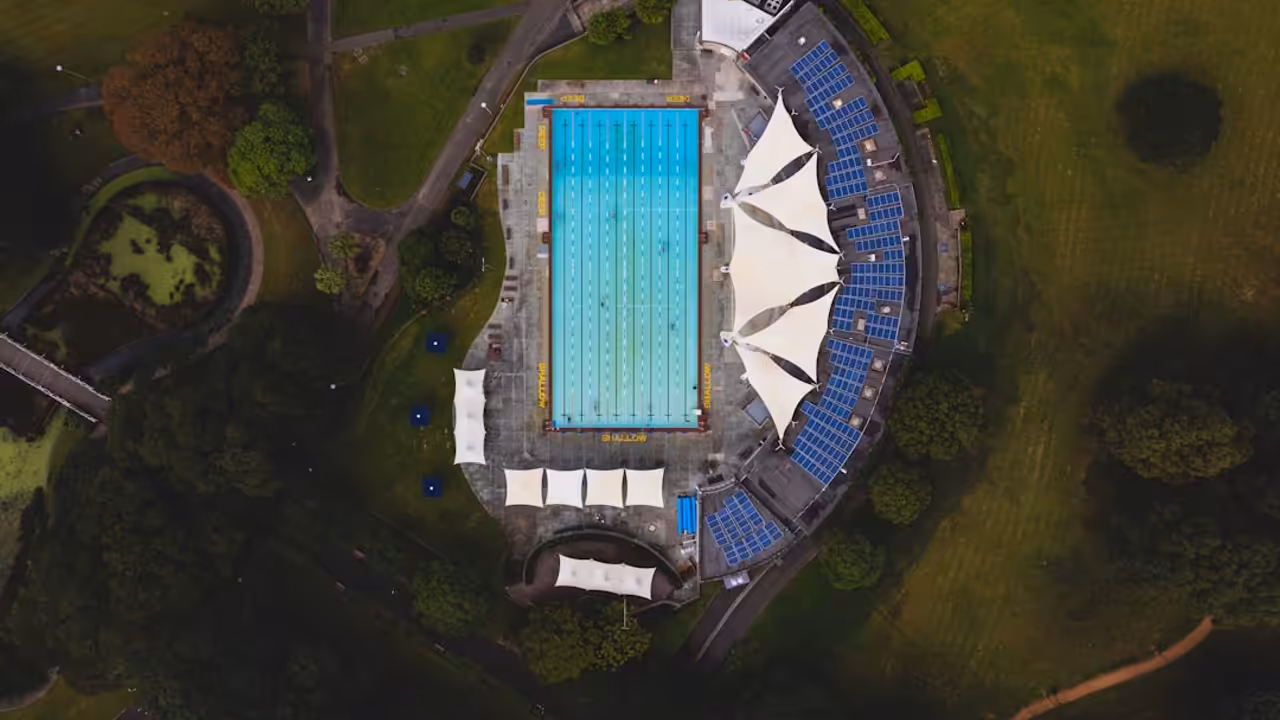 Bassin de natation de 25 mètres rénové, lignes d’eau tendues et vestiaires lumineux en arrière-plan