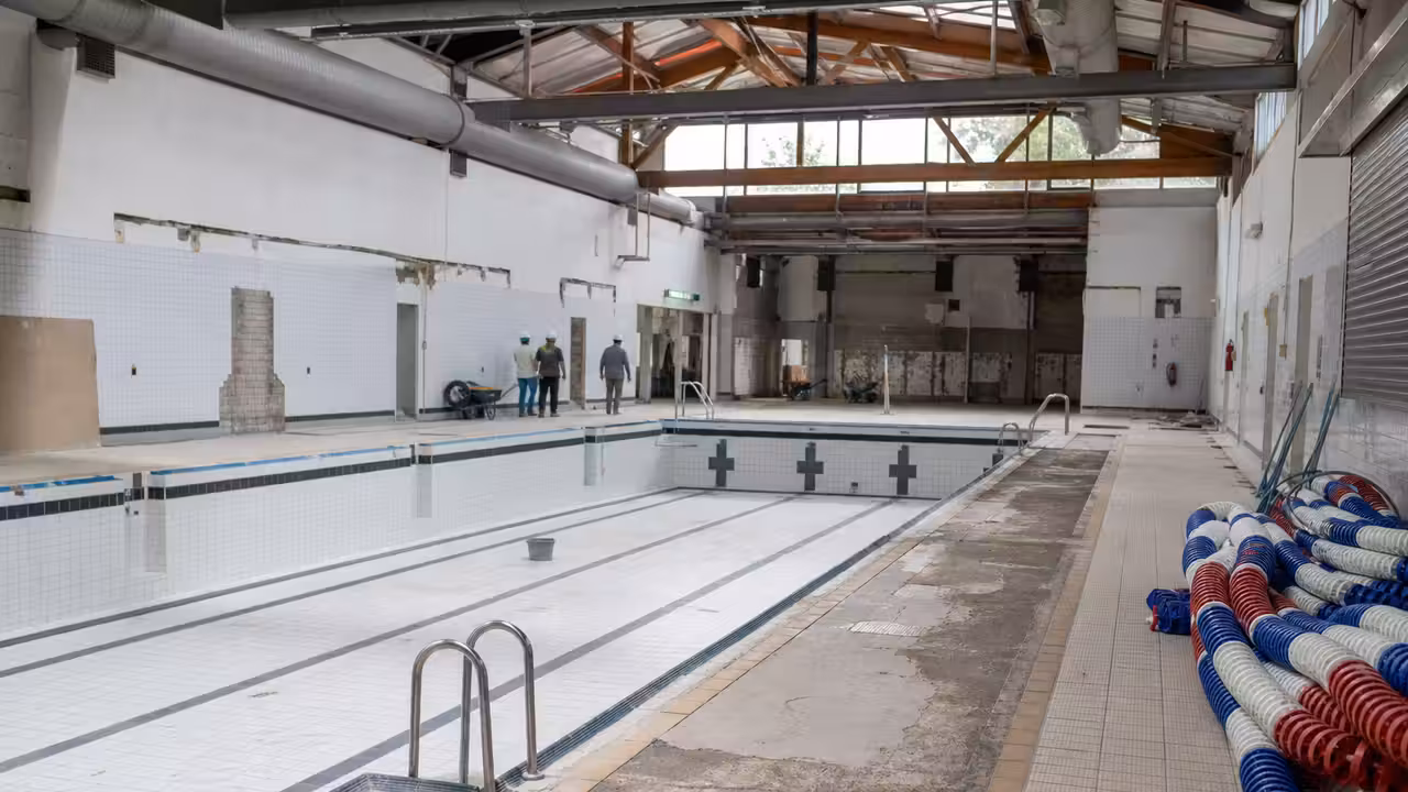 Bassin intérieur vide d’un centre nautique pendant une rénovation, avec lignes d’eau retirées et lumière naturelle