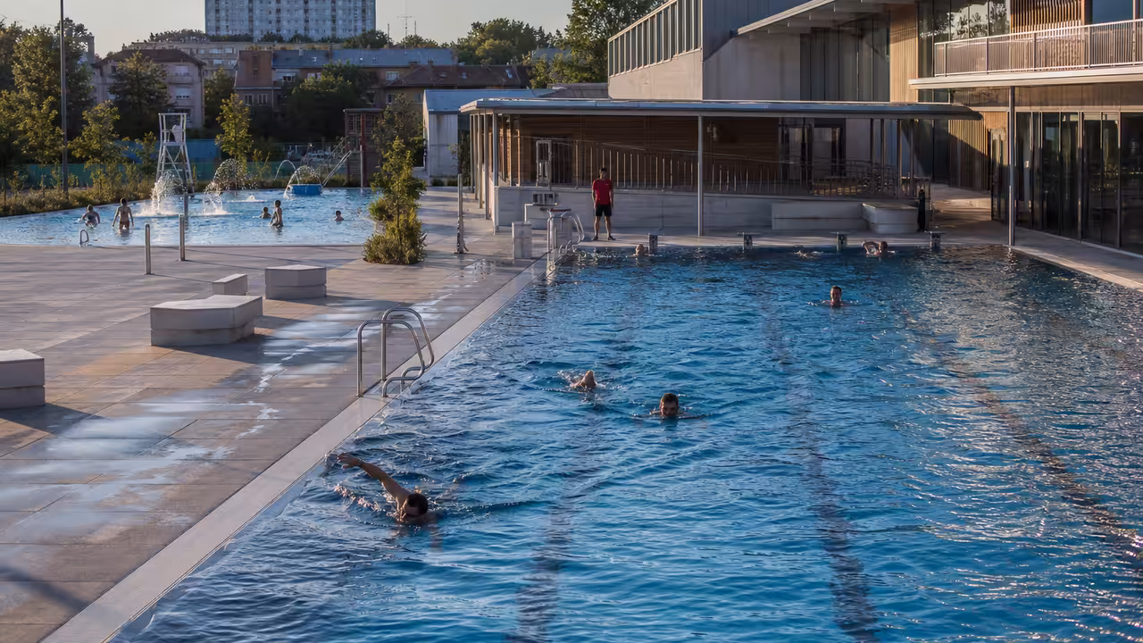 Bassin de nage extérieur et espace aquatique moderne fréquentés par des baigneurs dans une ville francilienne