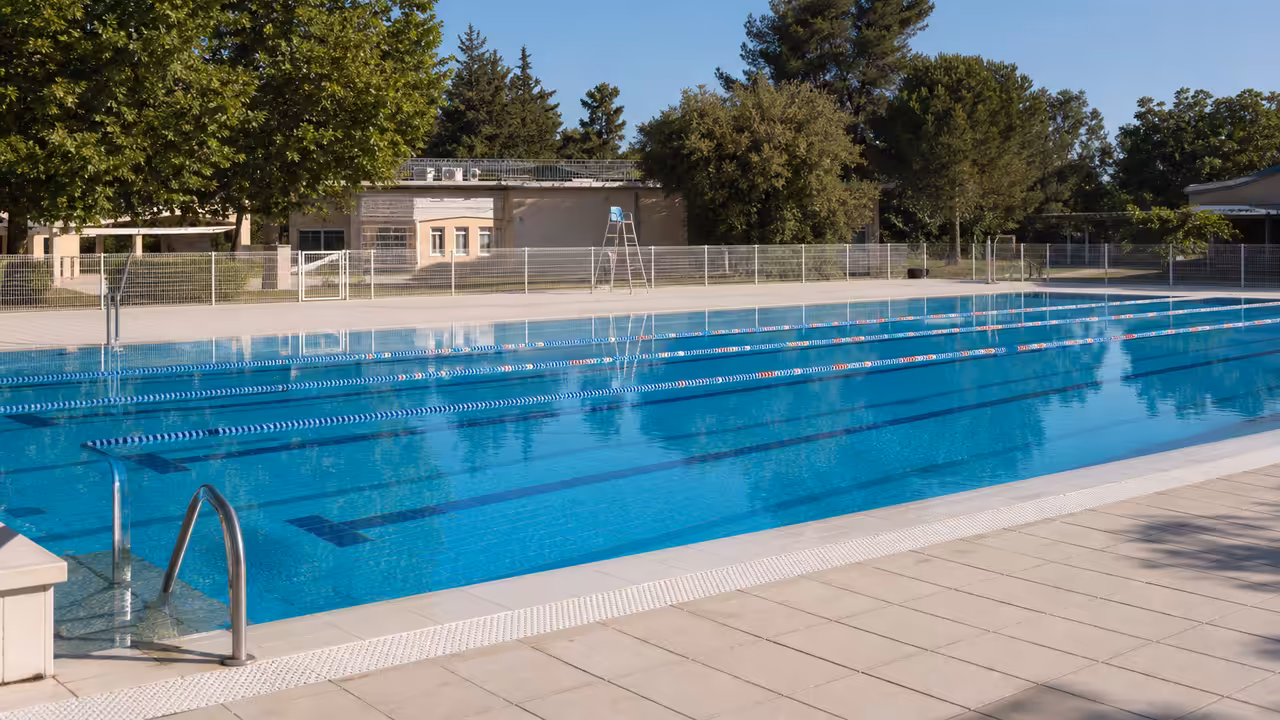 Bassin extérieur municipal calme et surveillé, prêt à accueillir les baigneurs au début de la saison estivale