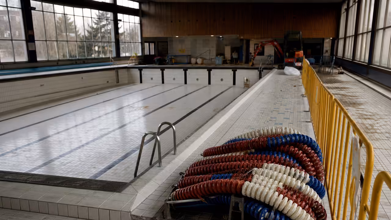 Bassin couvert municipal vide et sécurisé pendant des travaux de rénovation, avec lignes d’eau retirées