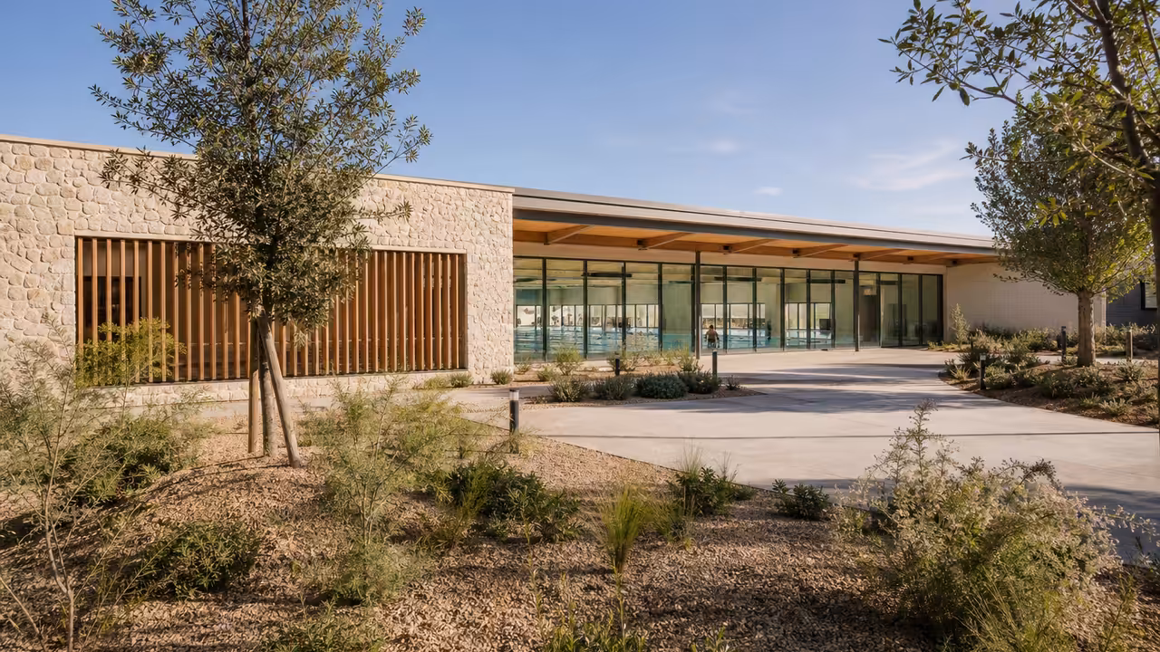 Façade paysagère d’un centre aquatique intercommunal avec bassin visible à travers de larges baies vitrées