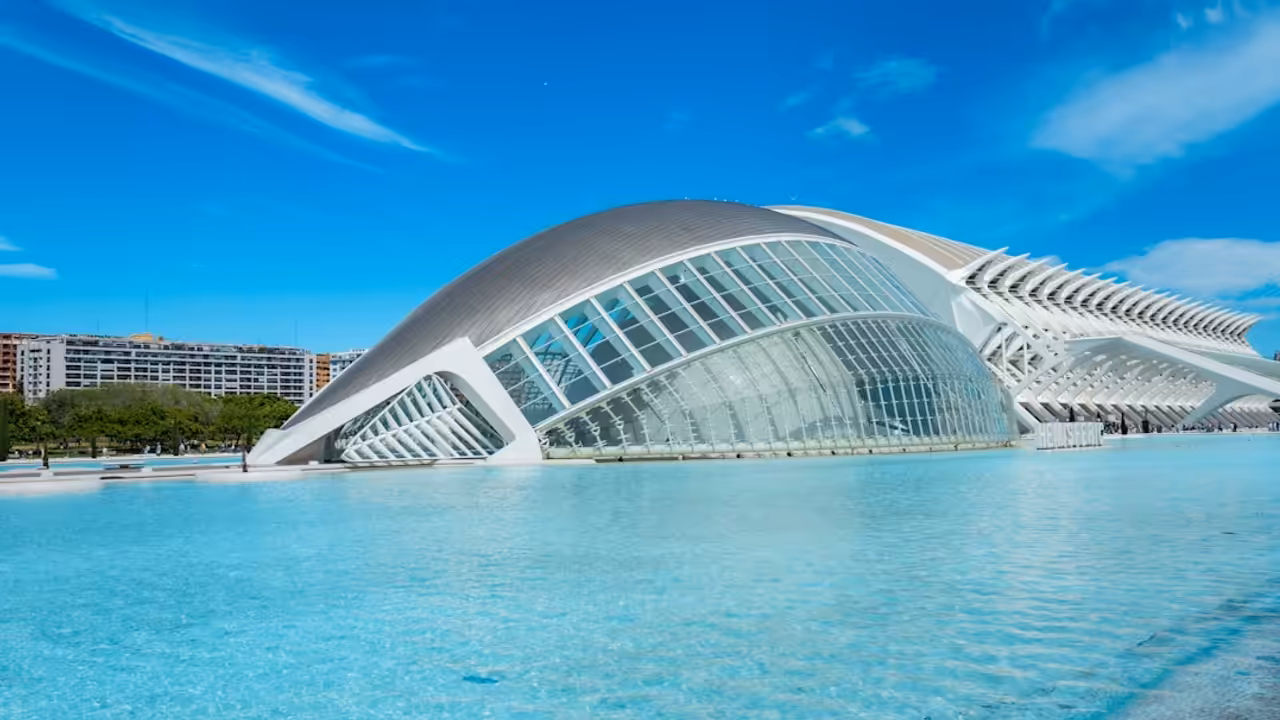 Abri bas télescopique fermé sur une piscine rectangulaire, avec terrasse minérale et jardin en arrière-plan