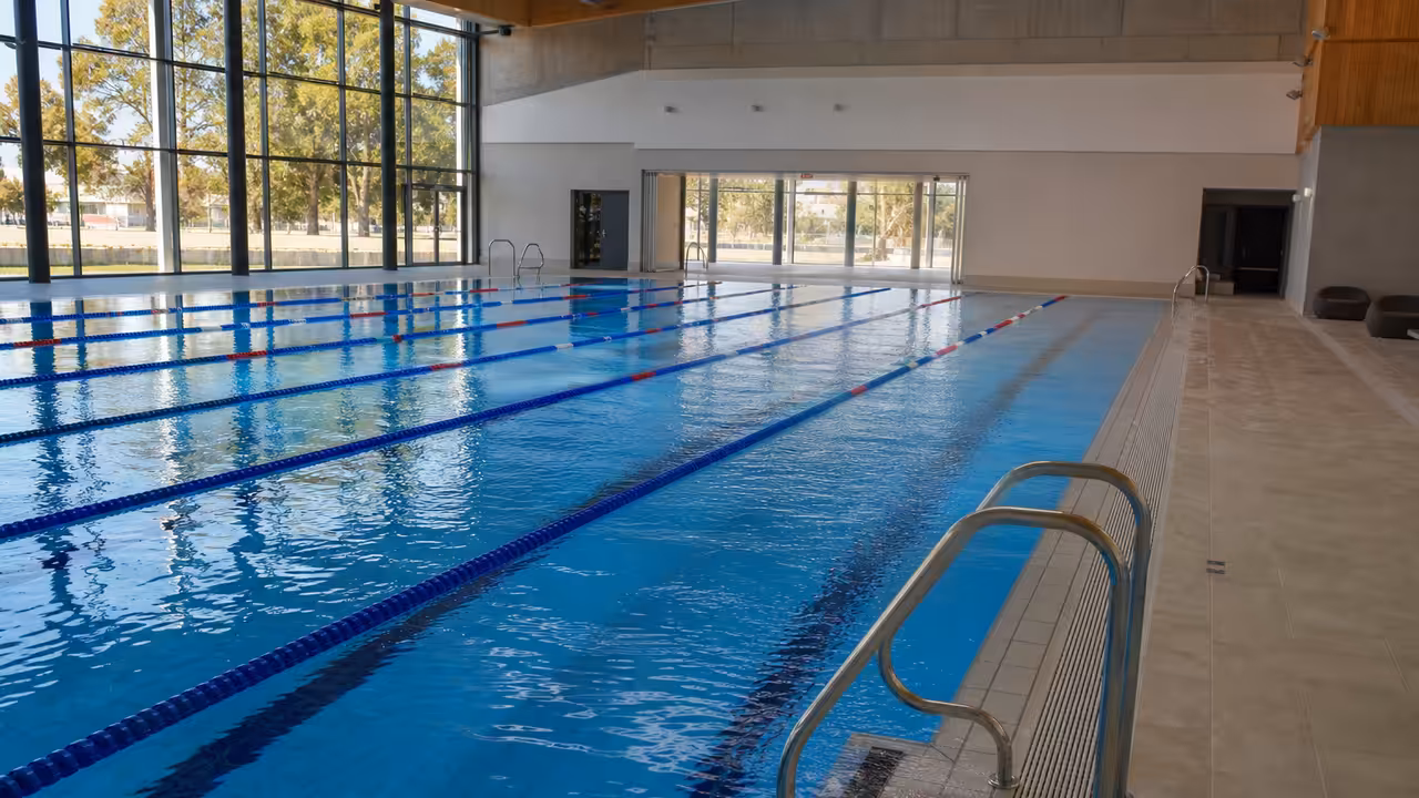 Bassin intérieur d’une piscine municipale avec lignes d’eau et local technique de filtration en arrière-plan