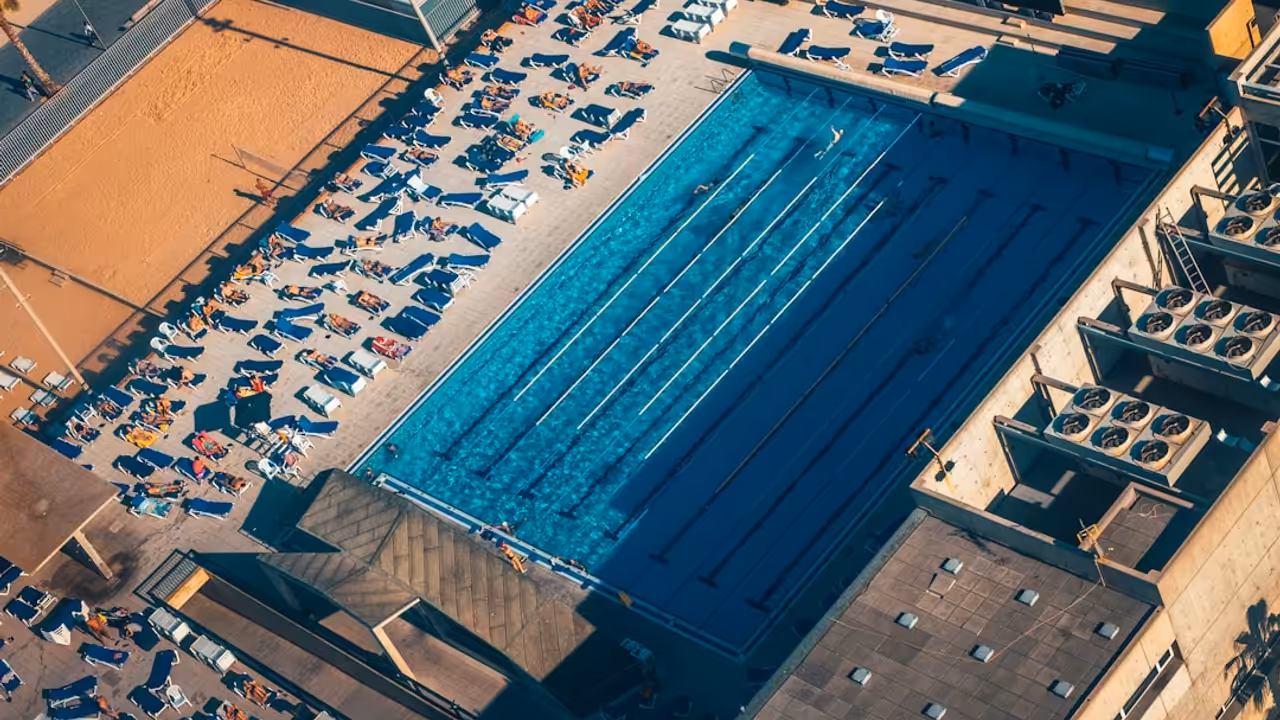 Bassin d’un centre aquatique municipal animé par des nageurs et des familles lors d’une journée estivale