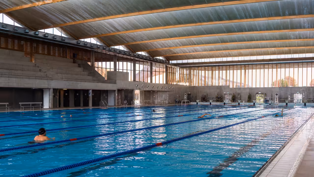 Bassin intérieur de 50 mètres d’une piscine publique moderne avec lignes d’eau et tribunes en arrière-plan