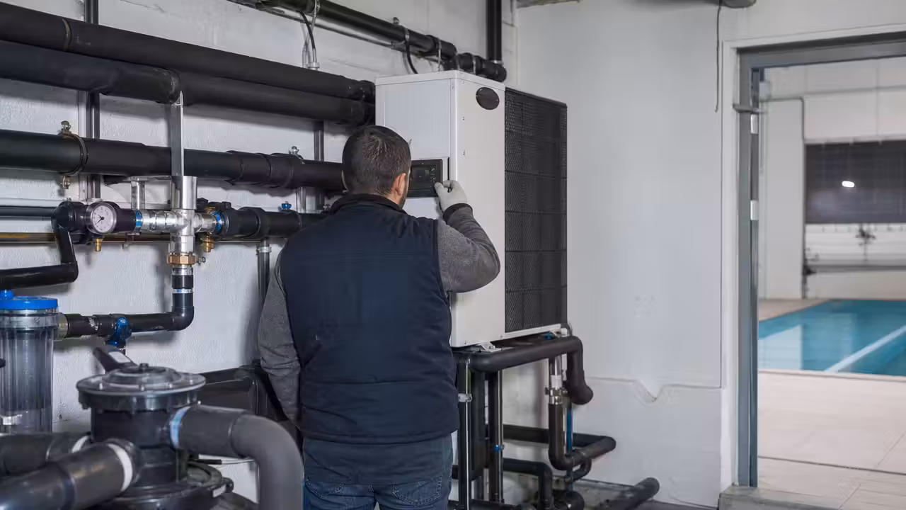 Technicien contrôlant les équipements de chauffage dans le local technique d’une piscine intérieure