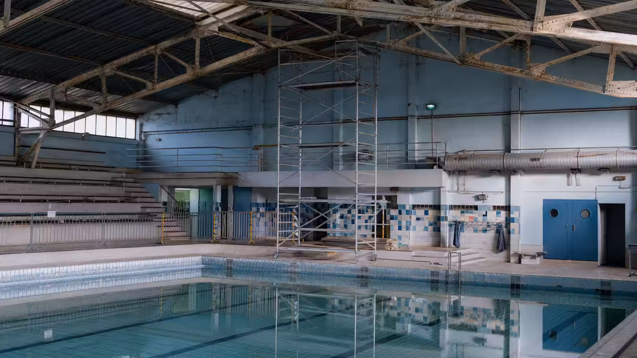 Structure métallique et toiture d’une piscine couverte inspectées depuis un échafaudage de chantier