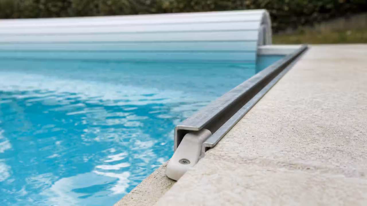 Rail latéral d'une bâche à barres de piscine avec l'embout d'une barre coincé dans la glissière
