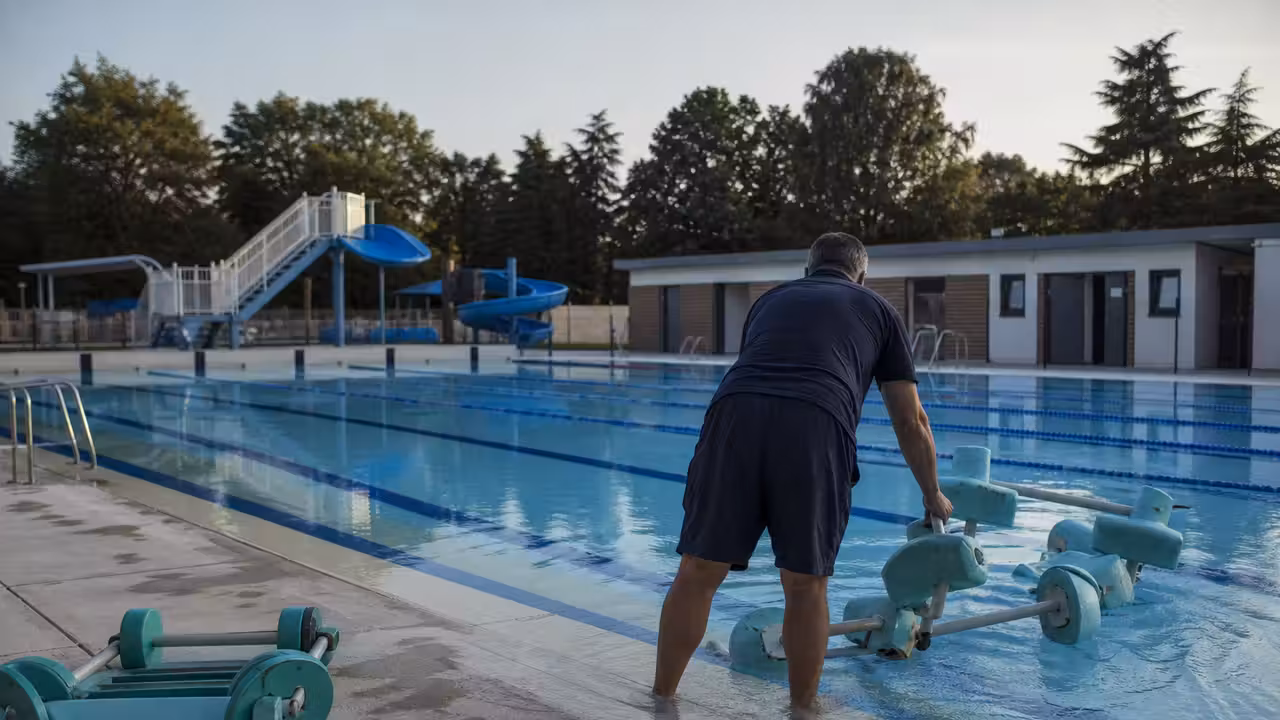 Bassin extérieur municipal avec lignes d’eau et personnel préparant des activités estivales