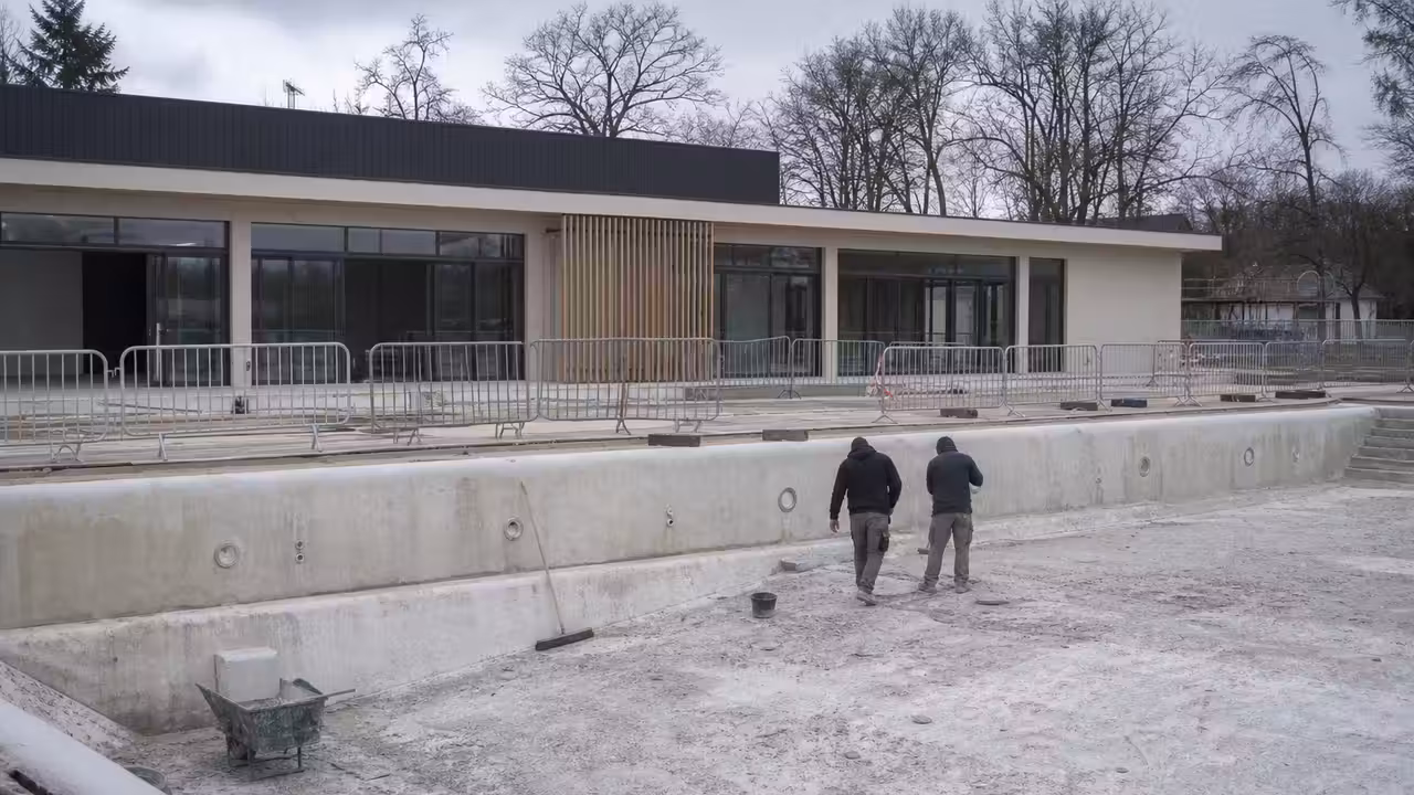Chantier de rénovation d’une piscine municipale avec bassin vidé et ouvriers au travail en arrière-plan
