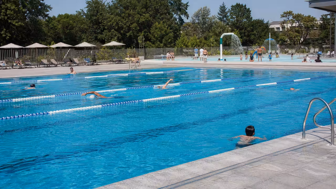 Bassin extérieur d’une piscine publique avec espaces de nage, jeux d’eau et zones ombragées