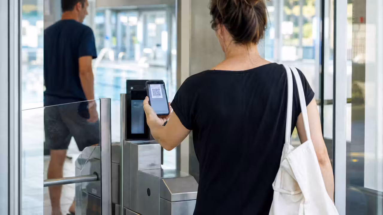 Usagers présentant un billet numérique à l’accueil lumineux d’une piscine publique moderne