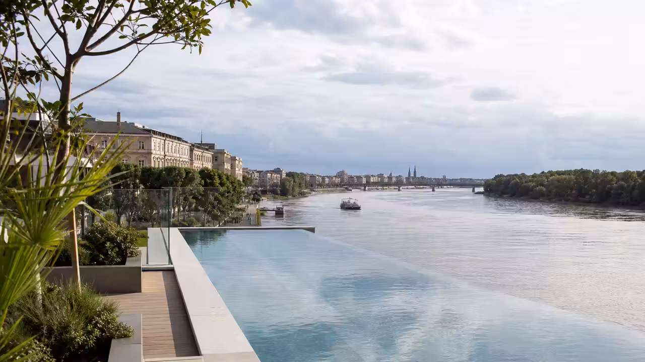 Piscine à débordement contemporaine sur une terrasse urbaine avec vue dégagée vers un fleuve