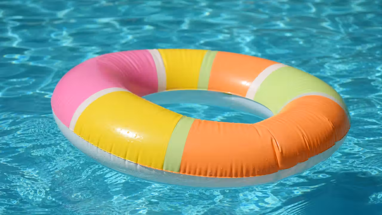 Bouée gonflable colorée aux tons pastel flottant à la surface d'une piscine turquoise