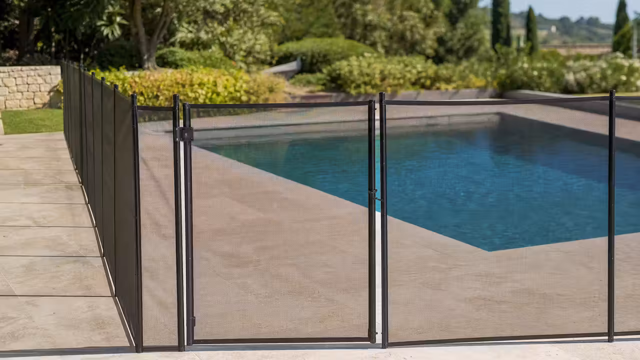 Barrière amovible en maille tendue installée autour d’une piscine familiale sur une terrasse en pierre