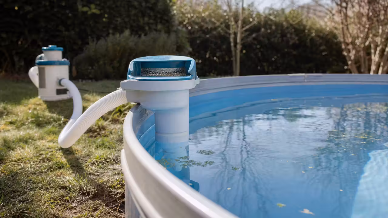 Skimmer suspendu fixé à une piscine hors sol tubulaire, aspirant des feuilles à la surface de l’eau