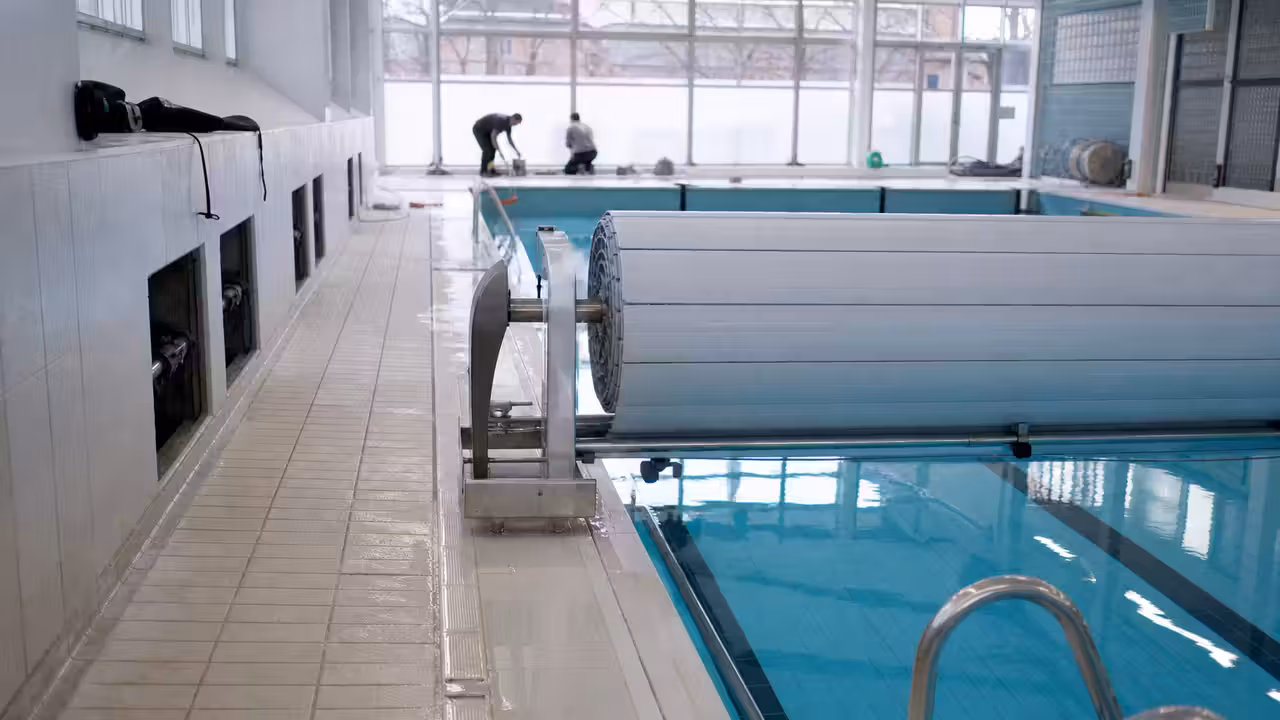 Bassin couvert vide durant des travaux techniques, avec couverture thermique enroulée au bord de l’eau