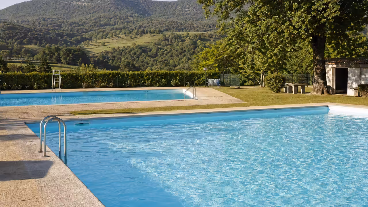 Bassin extérieur d'une piscine municipale entouré de pelouses, prêt pour une rénovation d'usage et d'énergie.