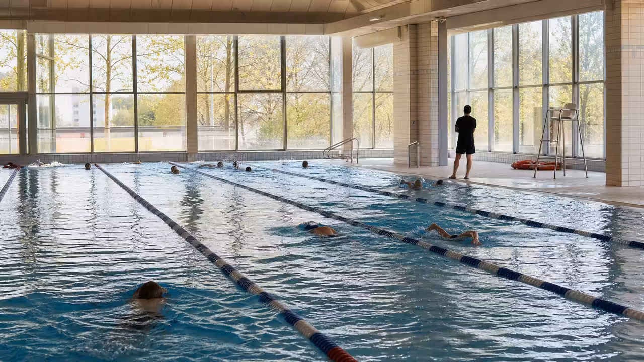 Bassin extérieur d’un centre aquatique animé par des familles et des nageurs sous un ciel printanier