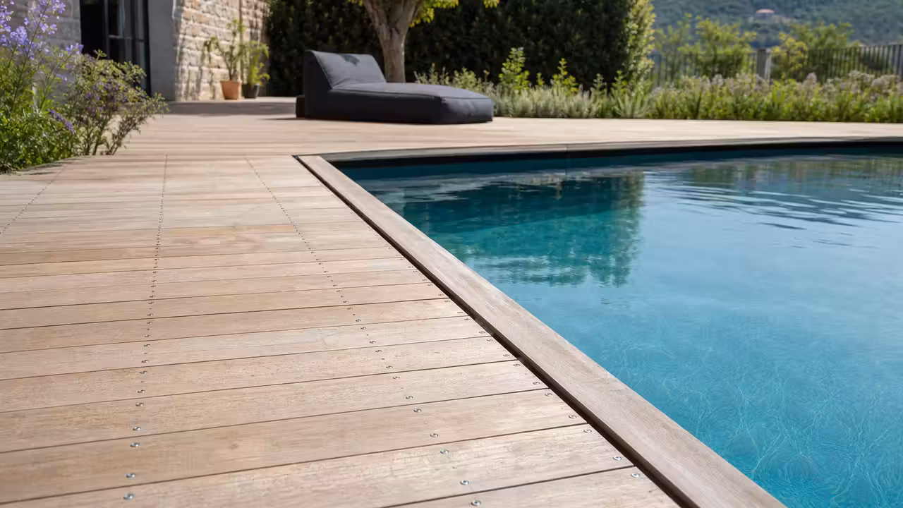Terrasse en bois naturel autour d’une piscine, avec lames espacées et drainage visible en bordure
