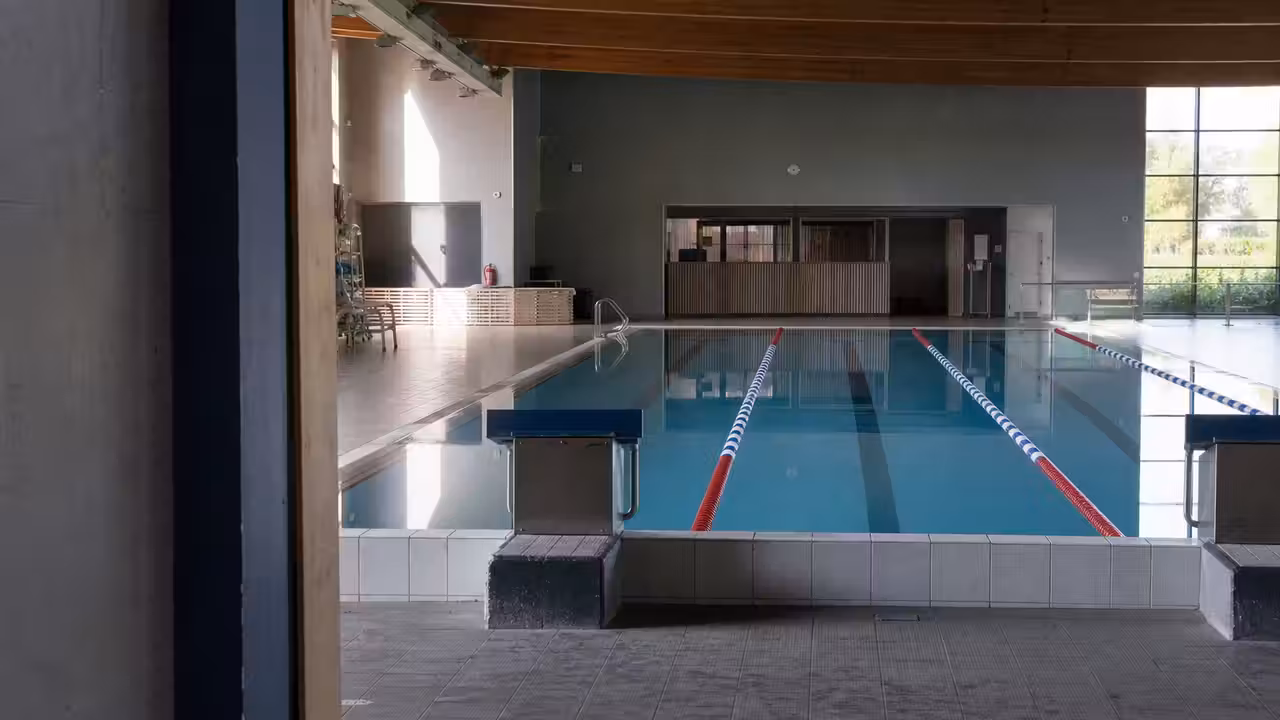 Entrée calme d’un centre aquatique public avec bassin intérieur vide lors d’une fermeture temporaire