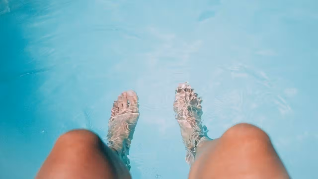 Volet roulant fermé sur une piscine extérieure, avec local technique discret et terrasse en bois au soleil