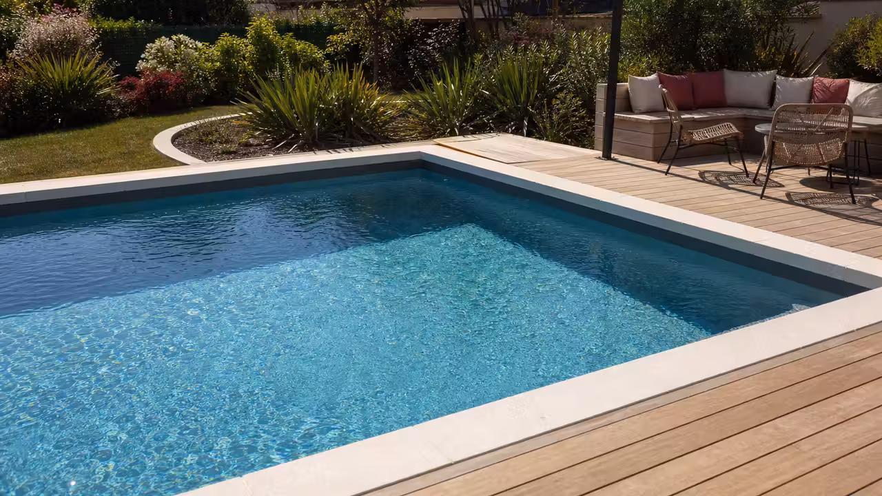 Piscine rectangulaire contemporaine avec terrasse en bois intégrée dans un jardin paysager lumineux