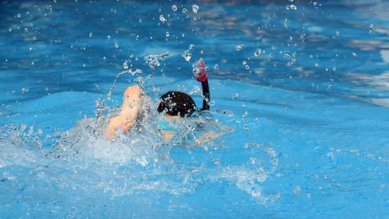 Nageuse de dos utilisant des haltères flottants dans une piscine privée aménagée pour l’aquagym