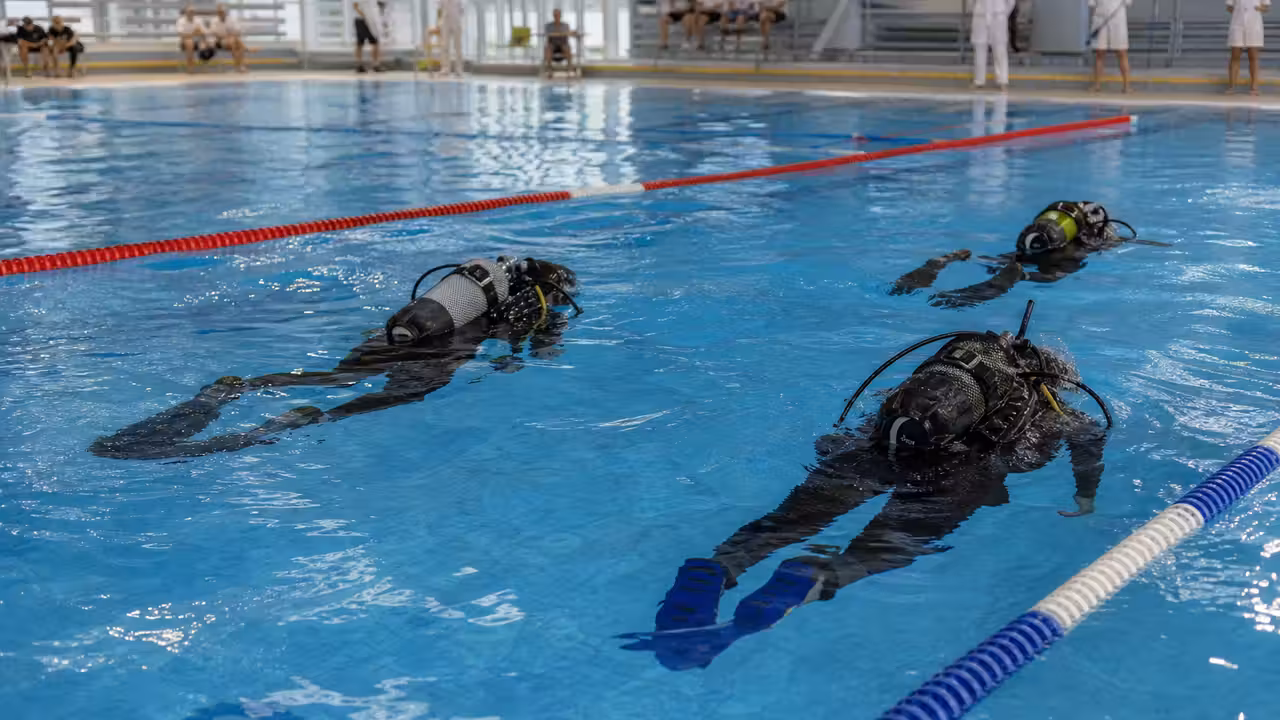 Compétiteurs adultes équipés de palmes et de bouteilles lors d’une épreuve de plongée sportive en piscine