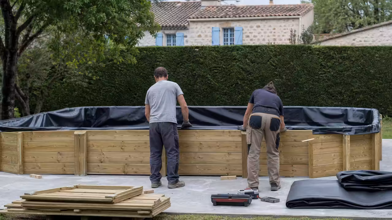 Piscine en bois hors-sol en cours d’installation sur une dalle plane dans un jardin arboré